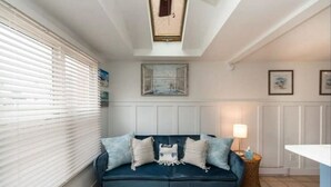 A cozy living room with a dark blue sofa, a small side table, and a window with blinds.