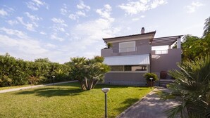 Een modern, twee verdiepingen tellend huis met een verzorgd gazon, een pad naar de ingang en een heldere lucht.