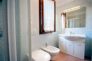 A bathroom with a toilet, bidet, sink, and mirror.