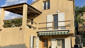 Ein zweistöckiges Gebäude mit Balkon, einer kleinen Veranda und einer Garagentür.