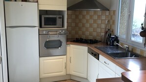 Eine kompakte Küche mit Kühlschrank, Mikrowelle, Backofen und Herd.