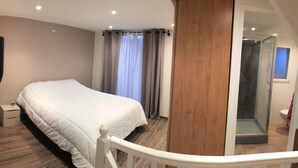 Ein Schlafzimmer mit einem Bett, einem Staubsauger, einem Nachttisch und einer Duschkabine.