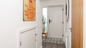 A hallway with a sign that reads "BEACH HOUSE RULES" and a door with a clock on the wall.