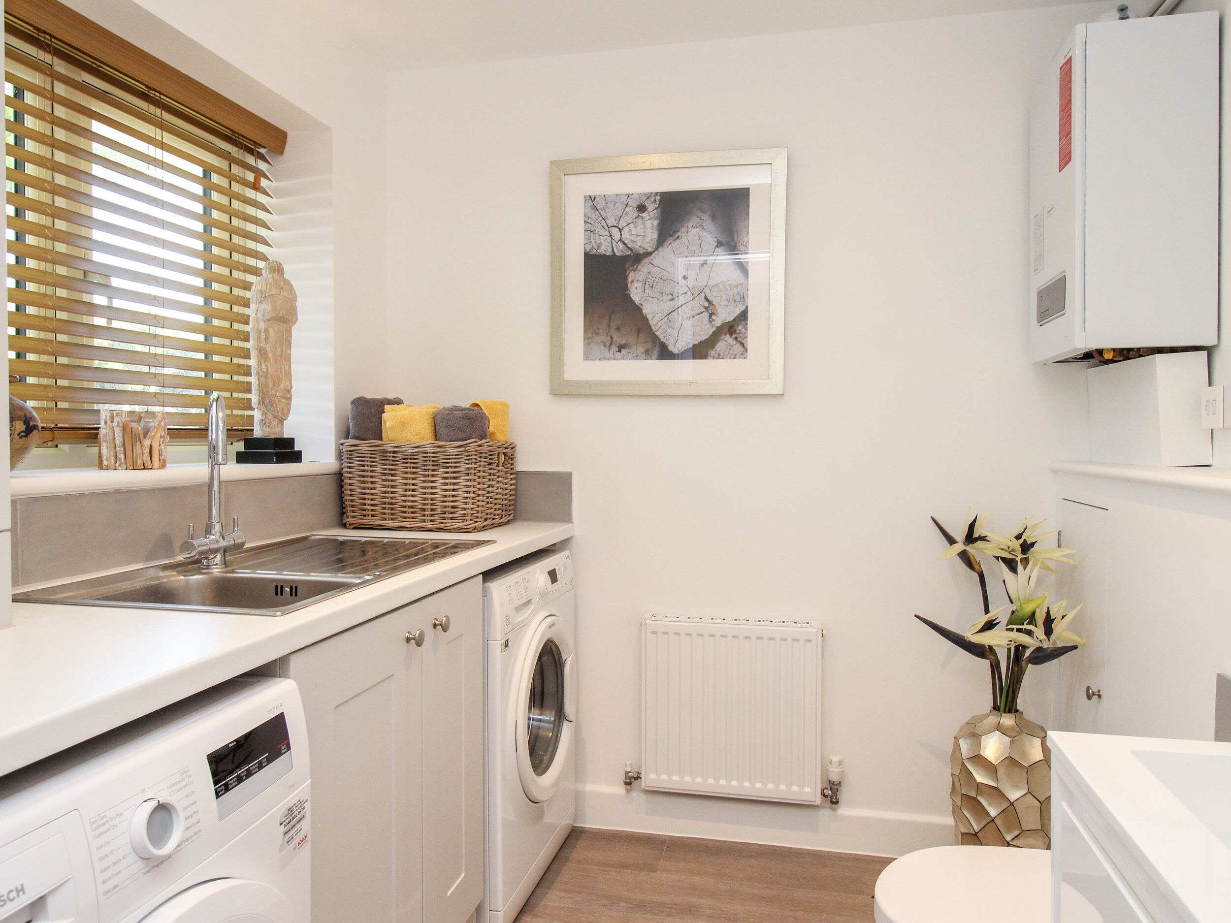 A compact laundry room with a washing machine, dryer, and a sink.