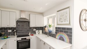 A modern kitchen with white cabinets, a black tiled backsplash, a built-in oven, and a white countertop.