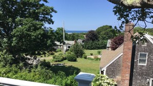 A residential area with a view of a house, a grassy yard, and a clear sky. - Sparkling home in quiet private beach community (Sandwich)