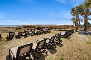 A beachside area with rows of lounge chairs and a wooden boardwalk leading to the beach. - Dunes Village by Elliott Beach Rentals (Myrtle Beach)