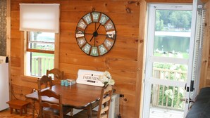 Un intérieur en bois comprenant une table à manger, des chaises, une horloge et une pancarte indiquant « Produits frais de la ferme ».
