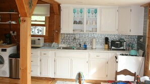 Une cuisine avec des meubles blancs, un pare-feu en carrelage et divers appareils, notamment un four à micro-ondes et un grille-pain.