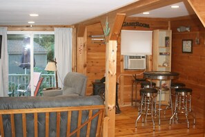 Een gezellige kamer met een bank, een tafel met barstoelen, en een bord waarop staat 