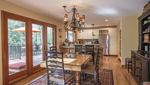 A spacious kitchen with a dining area, wooden flooring, and a chandelier.