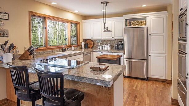 A modern kitchen with a large island, white cabinetry, and stainless steel appliances.