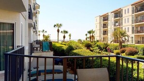 Ein Balkon mit Pool, umgeben von üppiger Vegetation und Palmen, mit Blick auf eine Wohngegend mit mehrstöckigen Gebäuden.