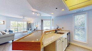A modern kitchen with a wooden island, a built-in sink, and a large window with blinds.