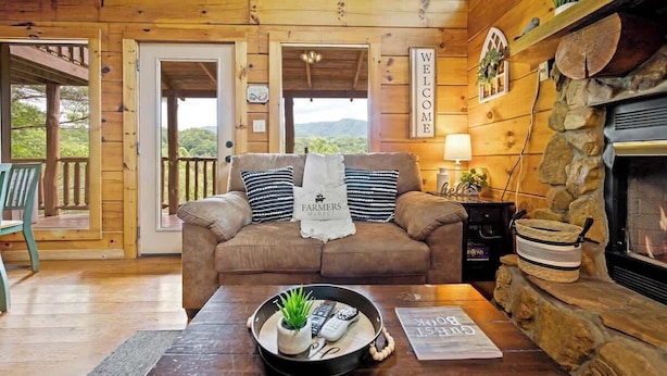 A wooden cabin interior with a sofa, a fireplace, and a welcome sign.