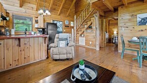 A cozy wooden cabin interior with a kitchen, dining area, and a staircase.