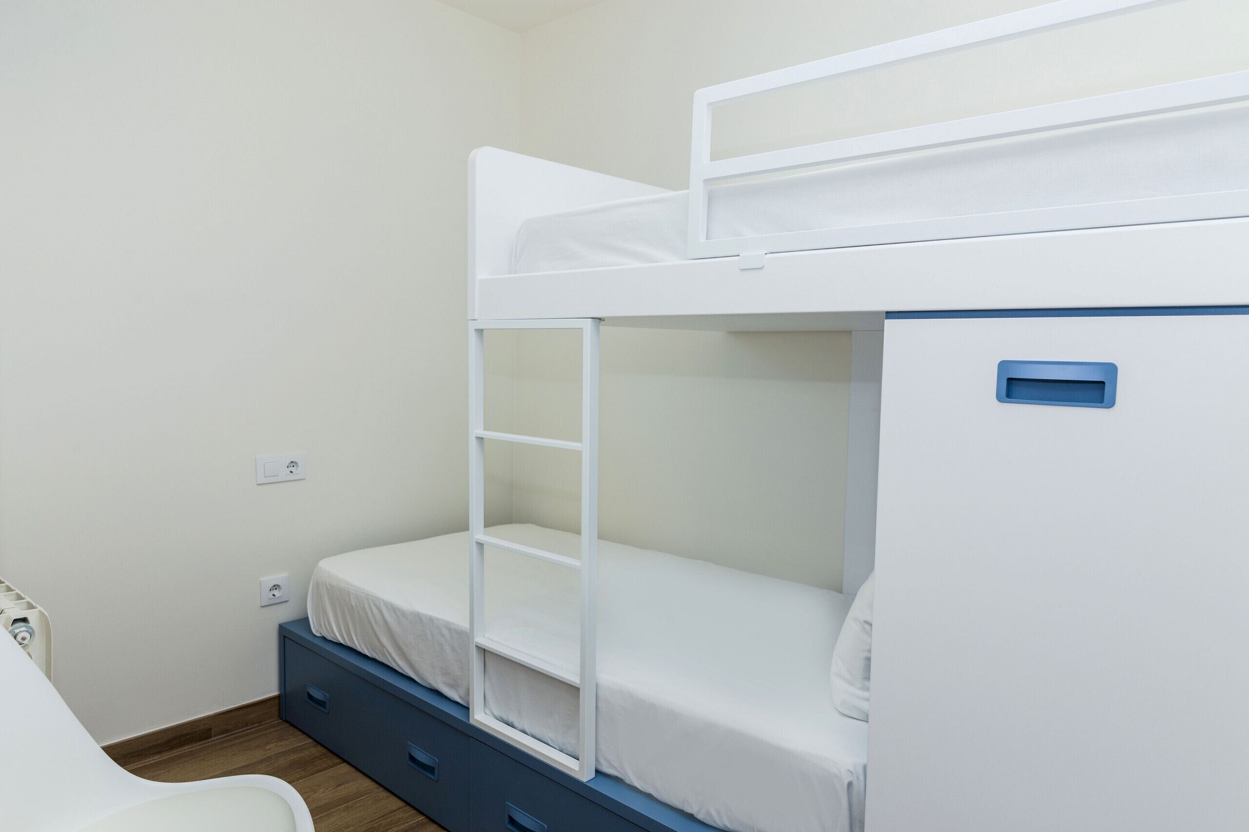 Una cama litera con una cama inferior y un cajón de escritorio debajo.