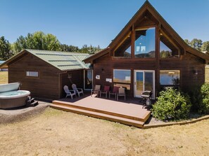 A wooden cabin with a hot tub, outdoor seating, and a deck.
