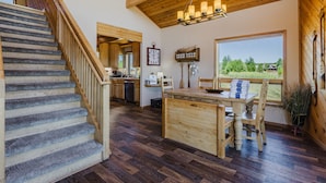 A wooden staircase leading to a kitchen with a dining area, a large window, and a view of the outdoors. - On Lake Hatcher. Fish right from home. Hot Tub. (Pagosa Springs)