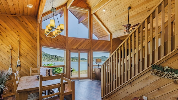 A wooden interior with a dining area, a staircase, and a view of the outdoors. - On Lake Hatcher. Fish right from home. Hot Tub. (Pagosa Springs)