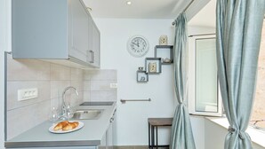 Una cocina compacta con un lavamanos, una mesita y una ventana con cortinas.