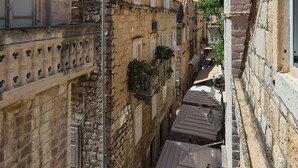 Una estrecha calle con edificios de piedra, un pasaje cubierto y algunas personas caminando.