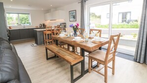A modern kitchen with a dining area, wooden furniture, and a view of the outdoors. - 3 Praa Cove (Penzance)