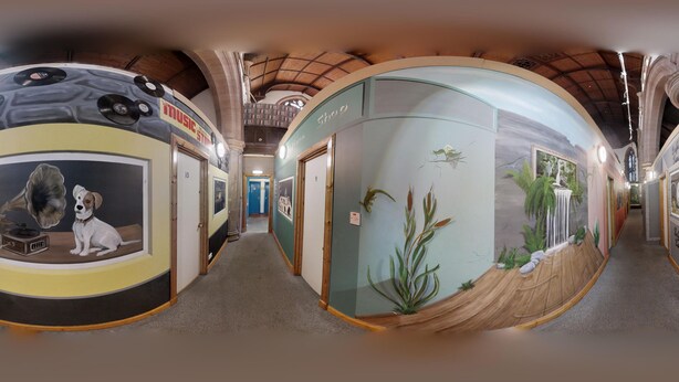 A corridor with a vintage train-themed wall, a glass display case with plants, and a wooden bench. - Belford Hostel (Edinburgh)