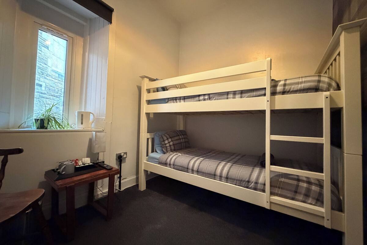 Huoneessa on kerrossänky, ikkuna, työpöytä ja tuoli.
