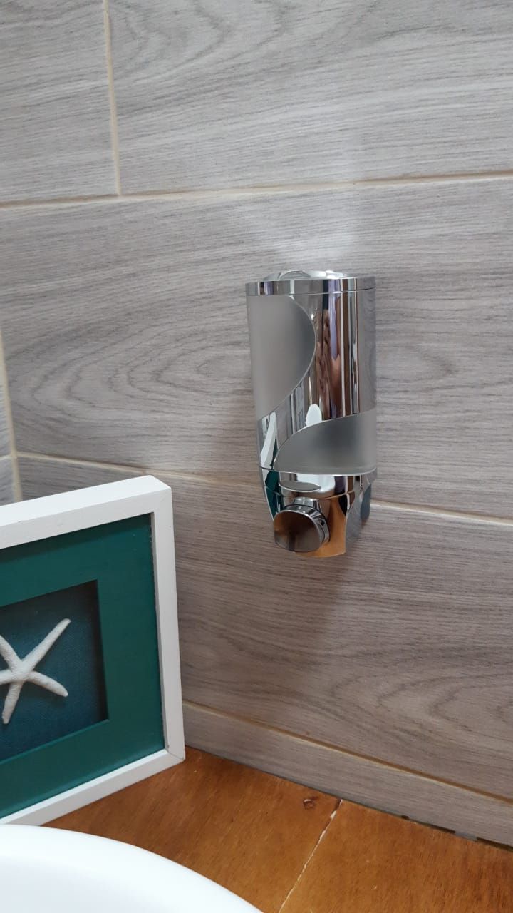 A bathroom with a wall-mounted sink, a framed picture of a starfish, and a tiled floor.