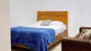 Un dormitorio con una cama, un sofá marrón y un equipo de aire acondicionado en la pared.