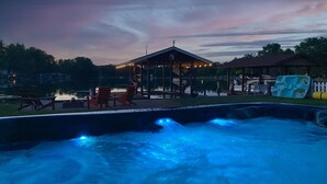 A hot tub area with seating and a gazebo, overlooking a body of water.