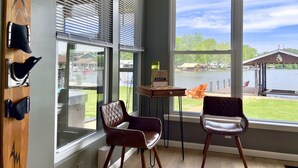 A room with large windows, a wooden table with a WiFi sign, and two chairs.