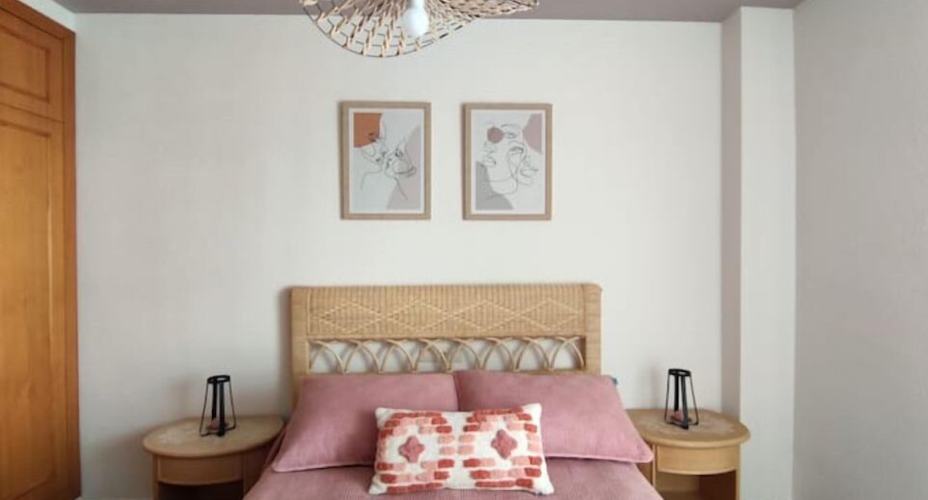 A bedroom with a bed, two bedside tables, and two framed artworks on the wall.