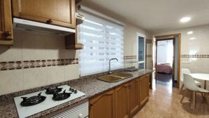 A kitchen with a gas stove, a sink, and wooden cabinets. - Avenue viewpoint (Albaida)