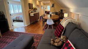 Un salon chaleureux avec un canapé, un ours en peluche et un coin repas comprenant une table et des chaises.