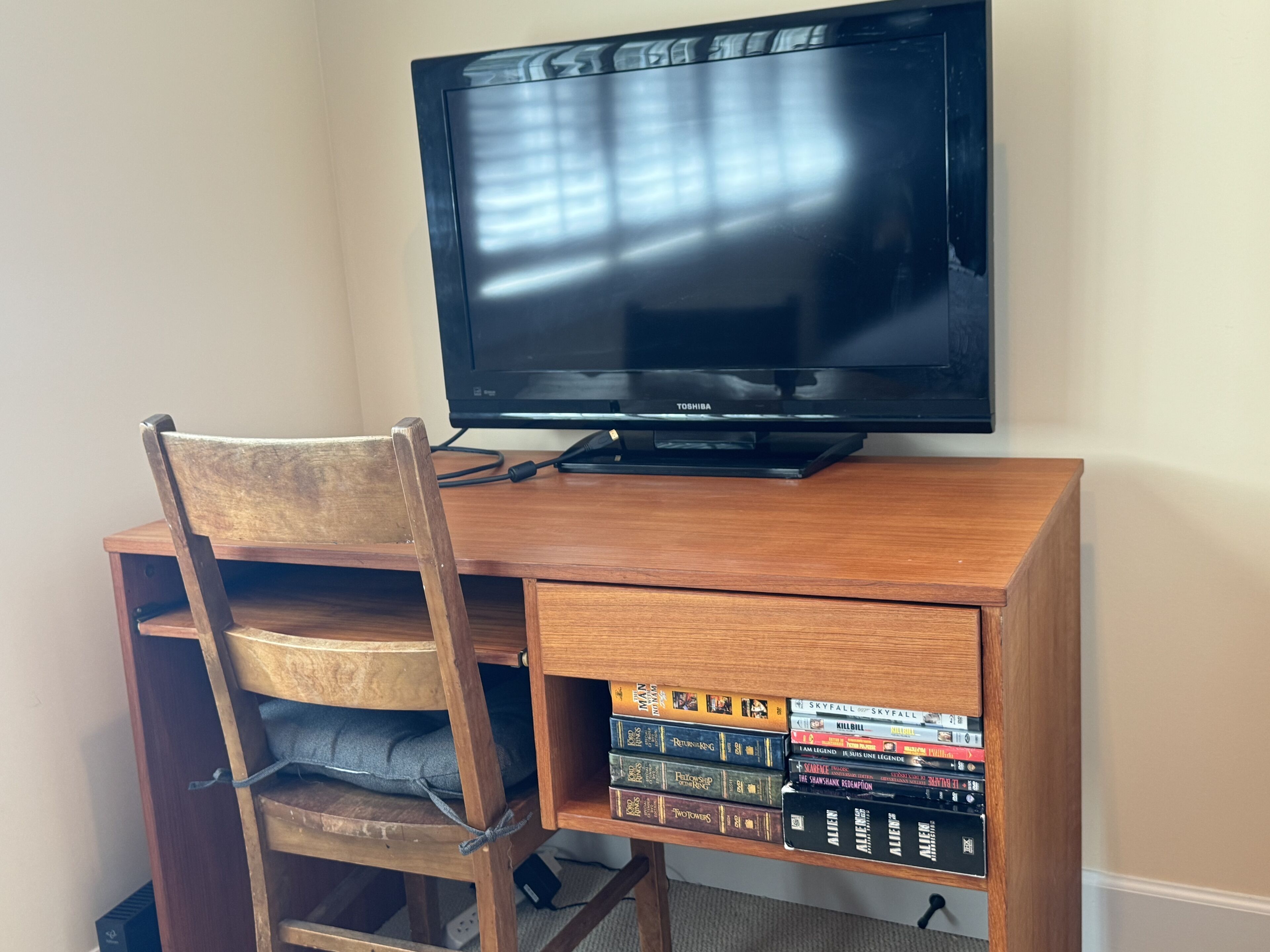 Un bureau en bois, avec une télévision et une pile de jeux vidéo.
