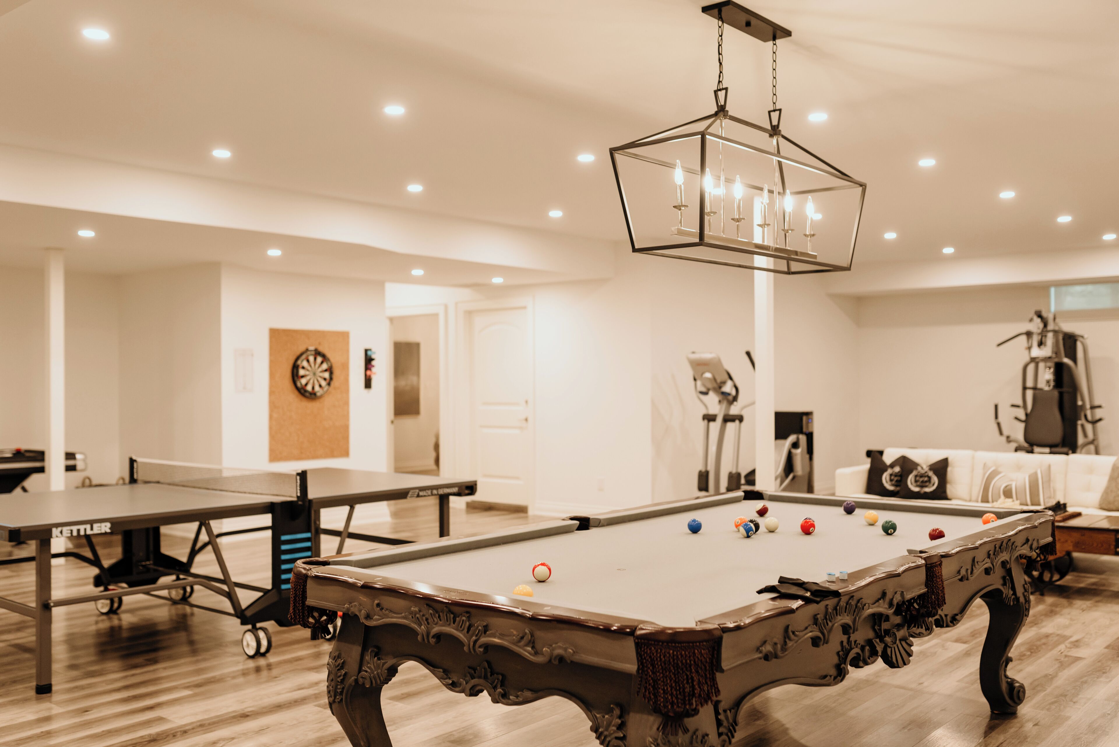 A pool table with balls, a ping pong table, and a billiards table in a well-lit room with a modern design.