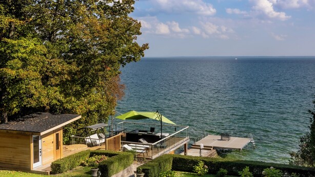 Une propriété au bord du lac comprenant un chalet en bois, une terrasse avec mobilier d’extérieur et une vue sur le lac.