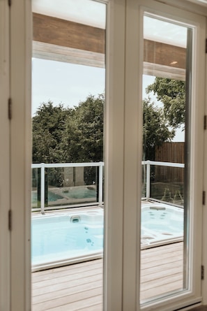 An indoor swimming pool with a wooden deck and a glass enclosure. - Luxury Lake Simcoe Waterfront Cottage (Innisfil)