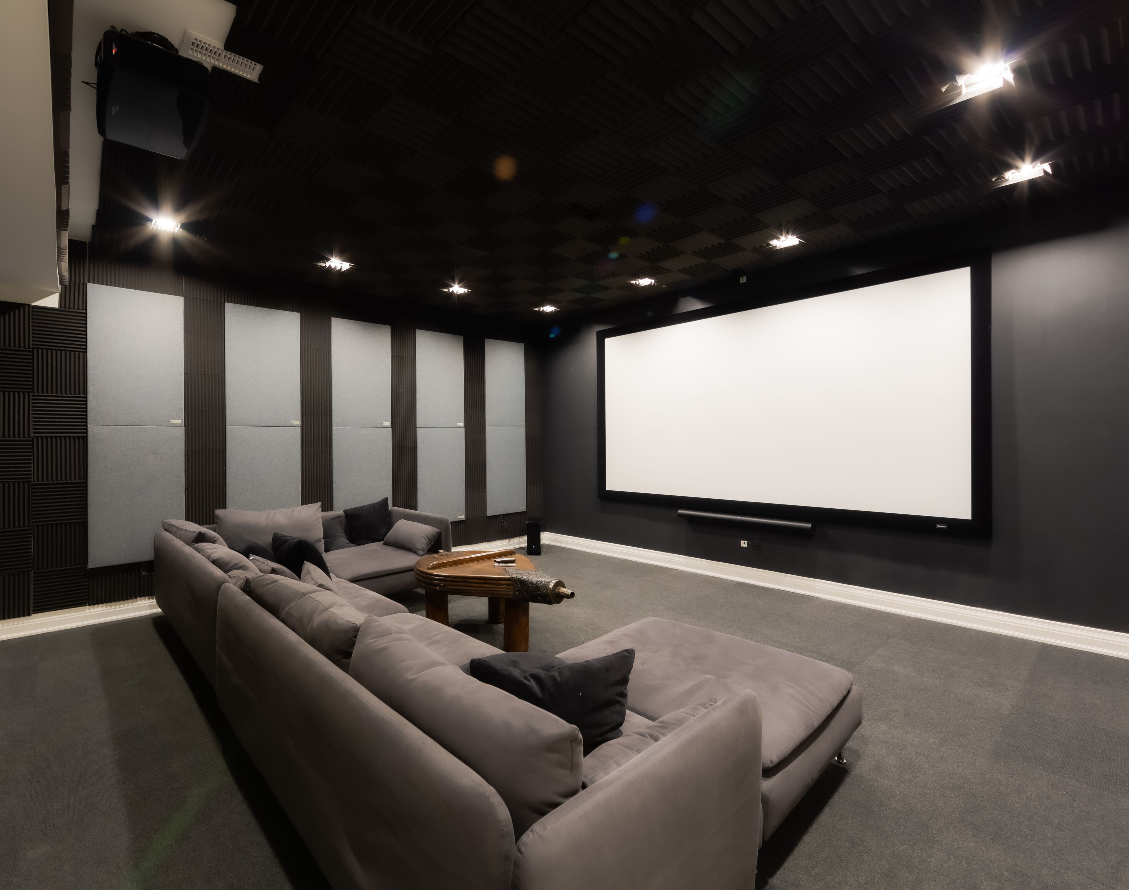 A home theater with a large screen, dark walls, and a sectional sofa.