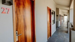 Un couloir avec des portes en bois, numérotées de 27, qui donnent accès aux chambres.