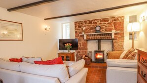 Una sala de estar acogedora con chimenea de piedra, un conjunto de sofás y un televisor.