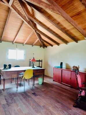 Une pièce avec un plafond en bois, une table à manger avec des chaises, une lampe et un buffet rouge.