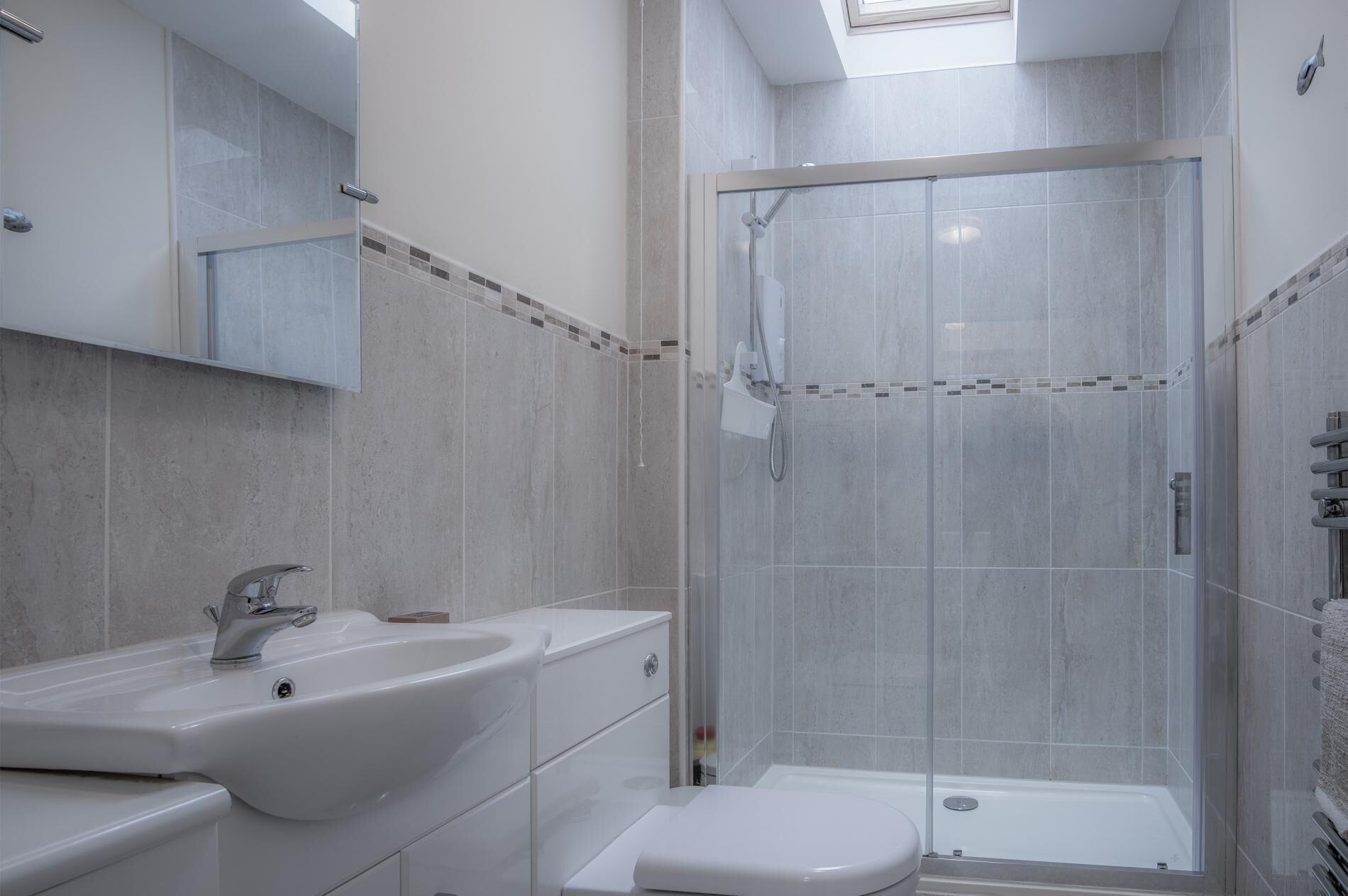 A modern bathroom with a glass-enclosed shower, a white sink, and a toilet.