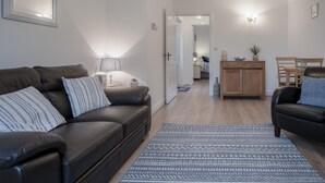 Una sala de estar moderna con un sofá de cuero, un tapete estampado y un mueble de madera.