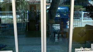 Entrada de hotel con felpudo, puertas de cristal y suelo de baldosas.