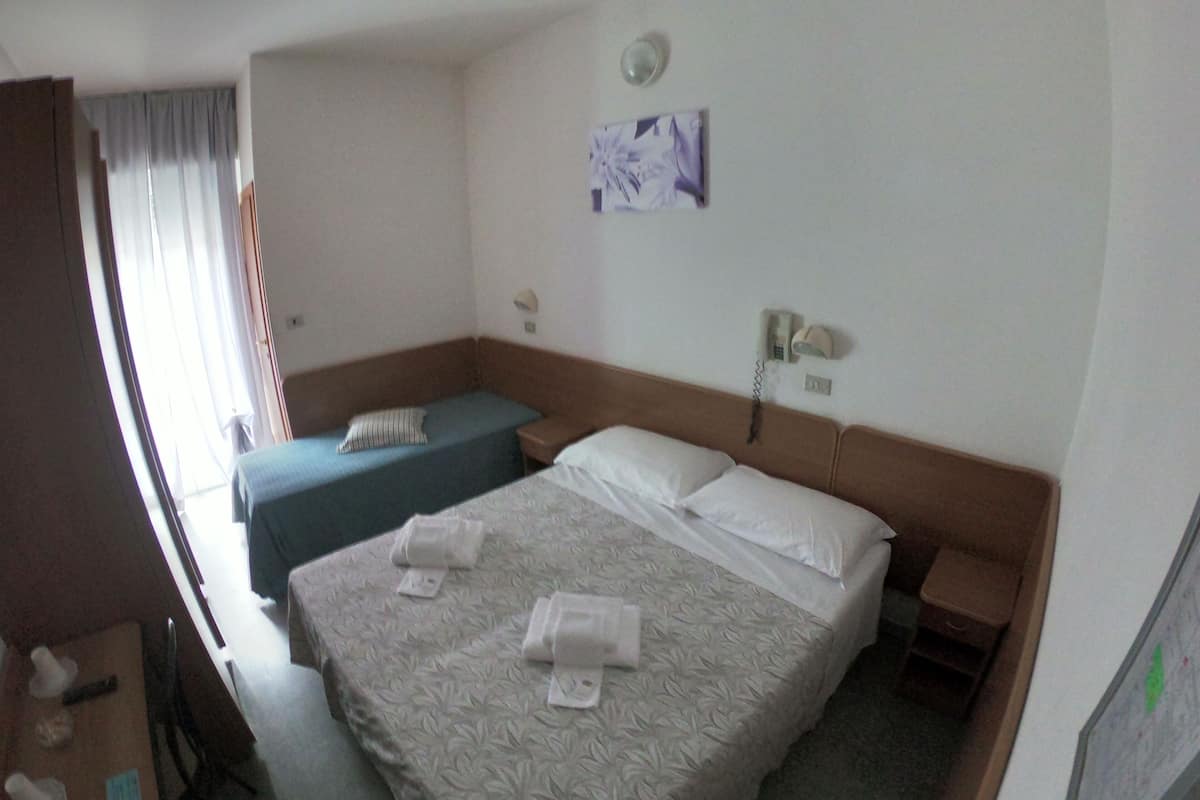 A hotel room with two beds, a desk, a chair, a telephone, and a window with curtains.