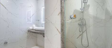 A modern bathroom with marble walls, a glass-enclosed shower, and a visible toilet.