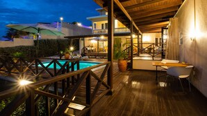 A wooden deck with a pool, outdoor seating, and a covered area with a table and chairs. - Apartment in the gated compound Jan Sofat near Jan Thiel Beach (Willemstad)